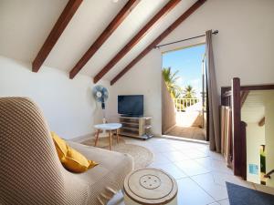 a living room with a couch and a television at Villa familiale, piscine privée, classée 3 étoiles in Sainte-Rose