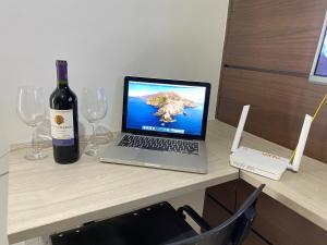 a laptop computer sitting on a desk with a bottle of wine at Flat aconchegante próximo a Pelinca in Campos dos Goytacazes