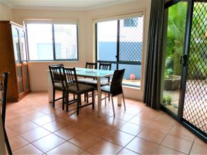 Un comedor con mesa y sillas y ventanas. en Grange Resort Hervey Bay, en Hervey Bay