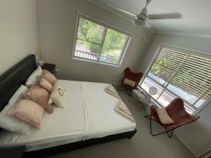 a bedroom with a bed with two chairs and two windows at Whitsundays Bayview Escape in Cannon Valley