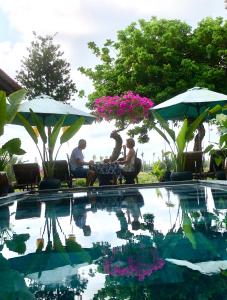 un grupo de personas sentadas alrededor de una mesa junto a una piscina en The Quin Riverside Villa, en Hoi An