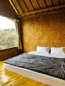 a bedroom with a large bed with a window at Saung Arjuna Syandana Resort in Ciwidey