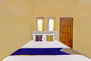 a bedroom with a bed with blue and yellow pillows at Capital O 91650 Hotel Pratama in Kolaka