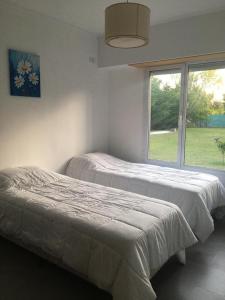 2 camas en una habitación con ventana en Casa Agustín en Balneario Claromecó