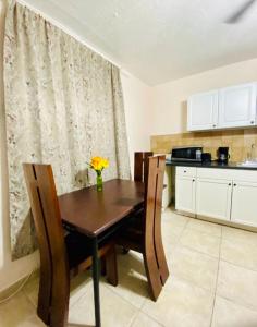 a kitchen with a wooden table and chairs with a vase of flowers at Hallandale Beach Motel in Hallandale Beach