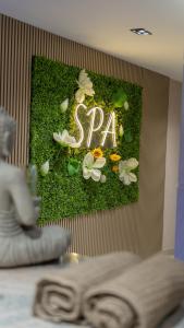 a spa sign on a wall with moss and flowers at Doanesia Premium Hotel & Spa in Tirana