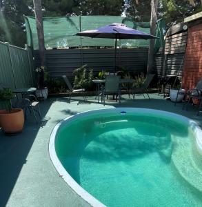 einen Pool mit einem Tisch und einem Sonnenschirm in der Unterkunft Country Roads Motor Inn in Narrandera