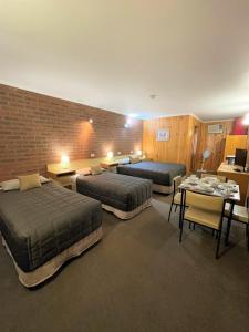 Habitación de hotel con 2 camas, mesa y sillas en Country Roads Motor Inn, en Narrandera