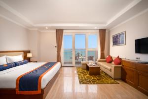 een hotelkamer met een bed, een bank en een televisie bij BlueSun Danang Beach Hotel in Da Nang
