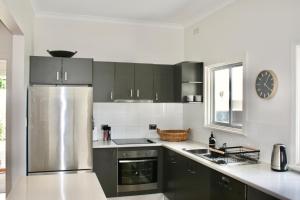 a kitchen with a stainless steel refrigerator and a window at Downtown Byron Bay Guesthouse in Byron Bay