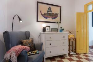 a bedroom with a blue chair and a dresser at Your Vintage Townhouse in Lagos