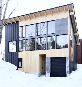 a house in the snow with a lot of windows at DREAM LIFE Onsen Villa in Niseko