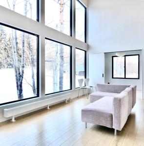 a living room with a couch and large windows at DREAM LIFE Onsen Villa in Niseko