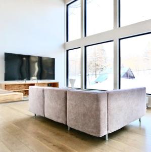 a living room with a large couch in front of windows at DREAM LIFE Onsen Villa in Niseko