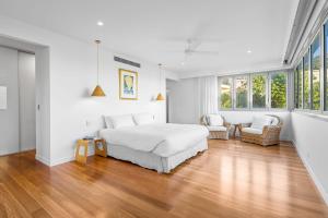 a white bedroom with a bed and two chairs at Daybreak at Currumbin in Gold Coast