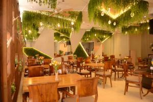 un restaurante con mesas de madera, sillas y plantas en Aura One Hotel, en Baguio