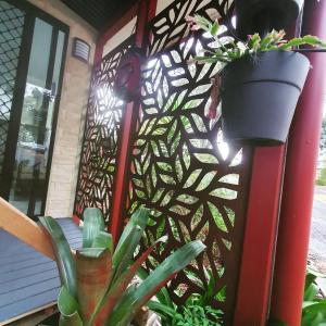 a fence with plants in front of a house at Rose City Caravan Park in Warwick