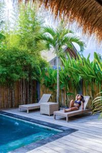 a woman laying on a chair next to a swimming pool at Akasia Villas in Gili Islands