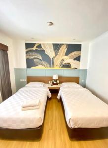 two beds in a bedroom with a painting on the wall at Cipta Hotel Wahid Hasyim in Jakarta