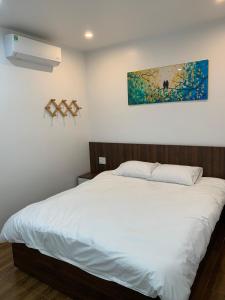 een slaapkamer met een wit bed en een schilderij aan de muur bij Adal Motel in Kiến An