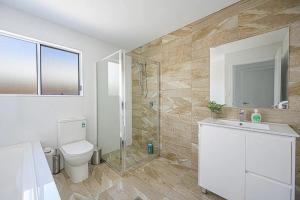 y baño con aseo, ducha y lavamanos. en Spacious 5 Bedroom 2.5 bathroom House in Gregory Hills, en Narellan