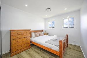 um quarto com uma cama, uma cómoda e 2 janelas em Spacious 5 Bedroom 2.5 bathroom House in Gregory Hills em Narellan