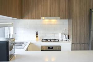 una cucina con ripiani bianchi e forno a piano cottura di Spacious 5 Bedroom 2.5 bathroom House in Gregory Hills a Narellan