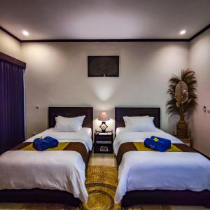two beds in a hotel room with blue towels on them at Pondok Baruna Frangipani in Nusa Lembongan