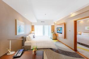 珠海市にあるHampton by Hilton Zhuhai Gongbei Portのベッドとデスクが備わる広い客室です。