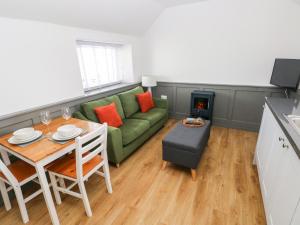 ein Wohnzimmer mit einem grünen Sofa und einem Tisch in der Unterkunft Star Cottage in Saundersfoot