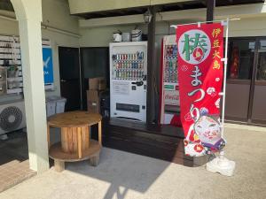 una tienda con un enfriador de bebidas y una mesa frente a ella en ゲストハウスKOIZUMI, en Oshima