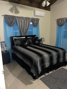 a black bed in a room with blue curtains at K&D EXCLUSIVE At the Vistas in Runaway Bay