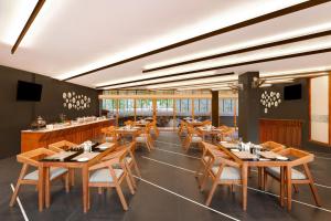 um restaurante com mesas e cadeiras de madeira e janelas em Keys Prima By Lemon Tree Hotels, Thekkady em Thekkady