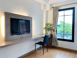 a living room with a tv and a chair and a window at View Dee BKK Airport Residence in Lat Krabang