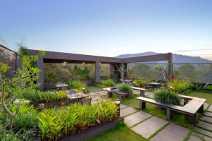 um pátio com mesas e bancos num jardim em Keys Prima By Lemon Tree Hotels, Thekkady em Thekkady