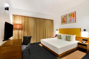 a bedroom with a bed and a desk and a television at Keys Prima By Lemon Tree Hotels, Thekkady in Thekkady