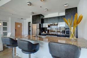 a kitchen with black cabinets and a counter with stools at Les Immeubles Charlevoix - Le 760516 in Quebec City