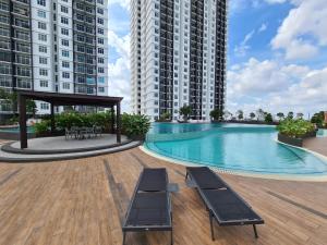 a swimming pool with two chairs and two tall buildings at Eid2 SKS Habitat Larkin-3BR Family Friendly up to 10Pax - 9 Beds- Free Wifi Pool Parking Gym & Preminum facilities in Johor Bahru