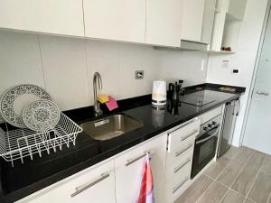 a kitchen with white cabinets and a black counter top at Nuevo y Cómodo depto tipo Estudio in Valdivia