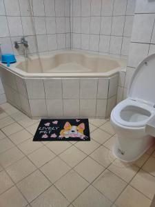 ein Badezimmer mit einer Badewanne, einem WC und einem Teppich in der Unterkunft Long Quan Ju in Wenquan