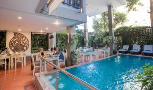 a group of people sitting at tables next to a swimming pool at King Grand Boutique Hotel in Phnom Penh