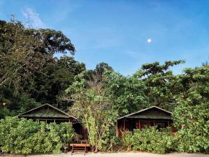 dos cabañas con un banco frente a algunos árboles en Raja Ampat Eco Lodge en Tapokreng