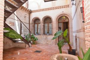 a courtyard of a building with a staircase and plants at Apartamentos La Casa Del Grial in Toledo