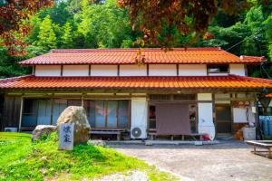 a house with an orange tiled roof and a bench at 一棟貸し宿Kusuburu House chartered accommodation in Okinoshima