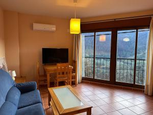 a living room with a couch and a tv and a table at El Mirador de Las Hurdes in Ladrillar