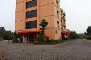 Hotel 678 Cawang powered by Cocotel في جاكرتا: مبنى كبير امامه شجرة