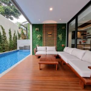 - un salon avec un canapé, une table et une piscine dans l'établissement Villa Daun at Dago Village, à Bandung