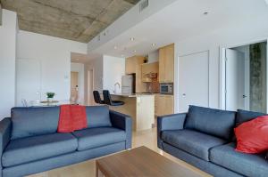sala de estar con 2 sofás azules y cocina en Les Immeubles Charlevoix - Le 760605, en Quebec