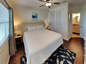 a bedroom with a large white bed with a ceiling fan at Baywatch #B1 in Pensacola Beach +15 photos