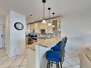 a kitchen with a breakfast bar with blue chairs at Baywatch #B1 in Pensacola Beach
